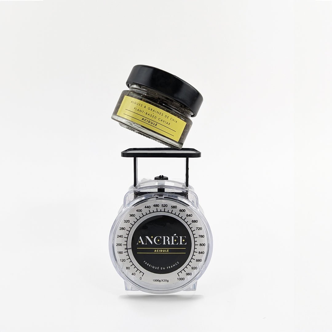 Pot de caviar végétal Acidulé posé sur une balance. Le pep's apporté par le mariage du citron et du yuzu est équilibré.
